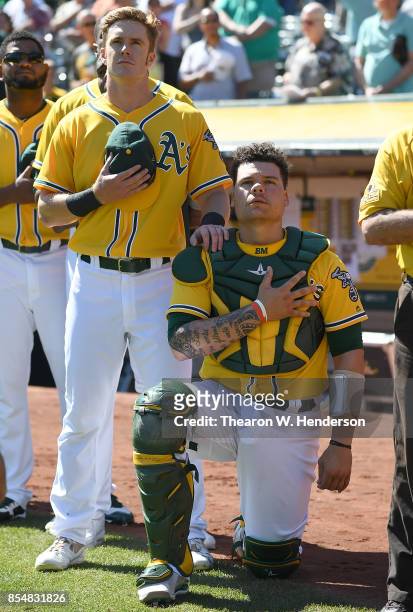 Bruce Maxwell of the Oakland Athletics kneels in protest next to teammate Mark Canha duing the singing of the National Anthem prior to the start of...