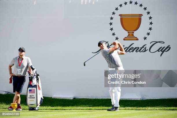 Matt Kuchar of the U.S. Team plays a tee shot as his caddie John Wood looks on prior to the start of the Presidents Cup at Liberty National Golf Club...