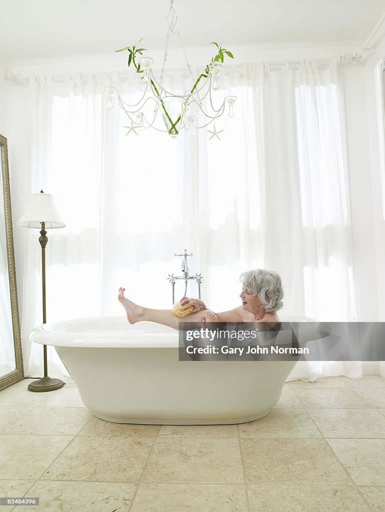 Senior woman relaxing in bath washing with sponge