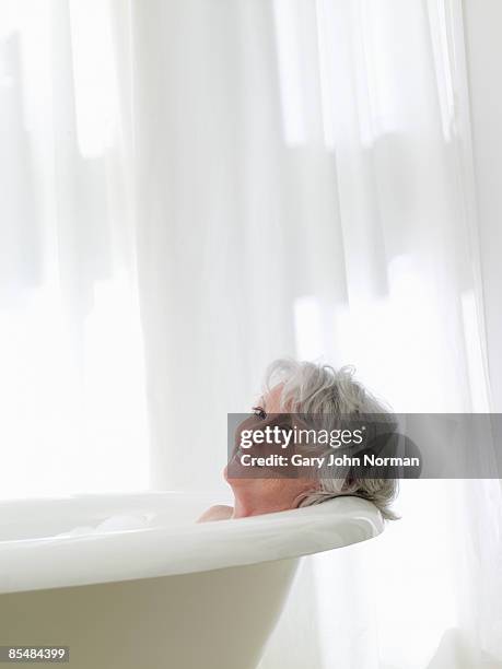 senior woman relaxing in bath. - norman elder stock-fotos und bilder