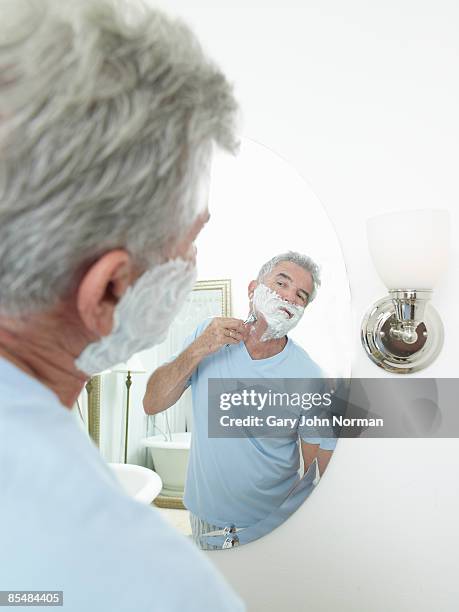 senior man shaving in mirror  - rasieren stock-fotos und bilder