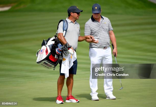 Charley Hoffman of the U.S. Team takes a golf ball from caddie Brett Waldman during a practice round prior to the start of the Presidents Cup at...