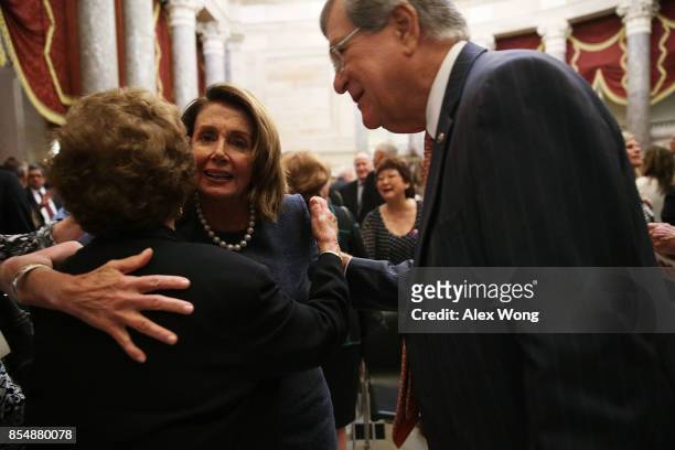House Minority Leader Rep. Nancy Pelosi hugs a guest as former Senate Majority Leader Trent Lott looks on during a memorial service at the National...