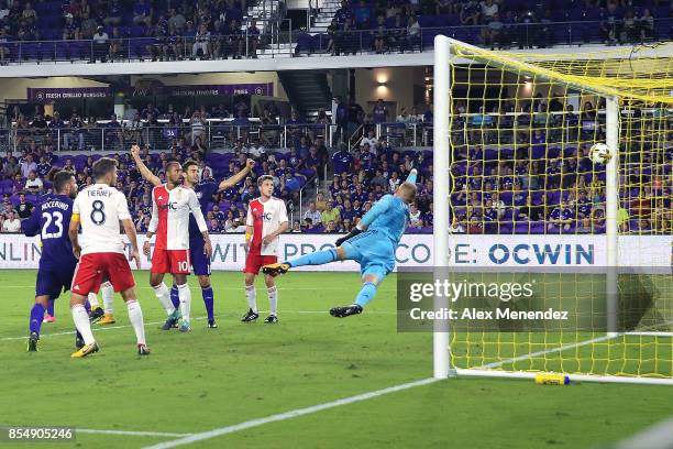 Cody Cropper of New England Revolution dives to block a shot attempt as Sebastian Hines of Orlando City SC scores a goal during a MLS soccer match at...