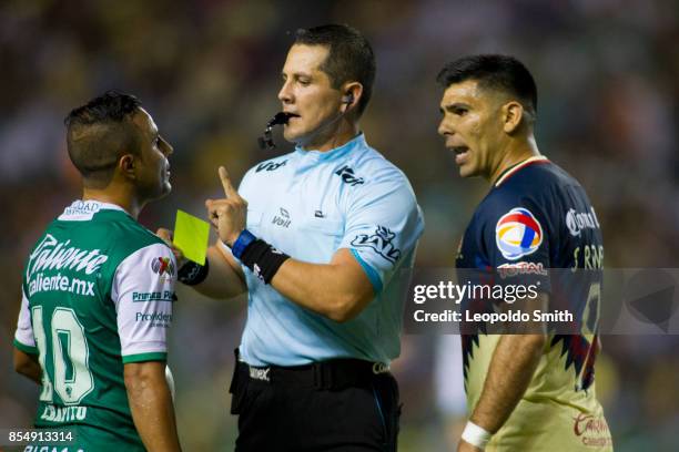 Referee Diego Montano Robles shows the yellow card to Luis Montes of Leon and Silvio Romero of America during the 11th round match between Leon and...