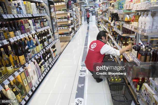 An employee stocks a liquor shelf at the Bic Camera Keio Chofu store, operated by Bic Camera Inc., inside the Trie Keio Chofu Shopping Center in...