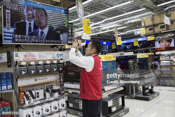 An employee adjusts a store display at the Bic Camera Keio Chofu store, operated by Bic Camera Inc., inside the Trie Keio Chofu Shopping Center in...