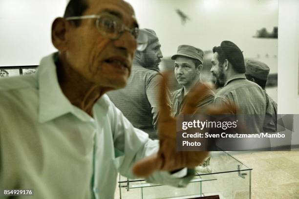 Historian Faustino Moriano talks about Che Guevara in front of a photo that shows Che with Fidel Castro and his brother Raul Castro , in the Che...