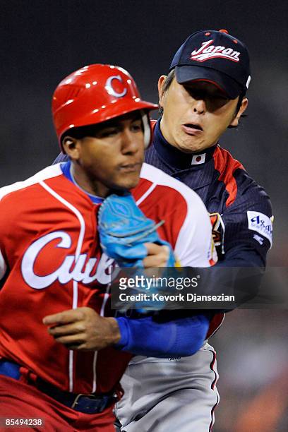 Hisashi Iwakuma of Japan tags out Alfredo Despaigne of Cuba as he runs to first base during the 2009 World Baseball Classic Round 2 Pool 1 Game 5 on...