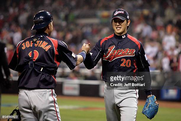 Kenji Johjima of Japan congratulates starting pitcher Hisashi Iwakuma after he leaves the game without giving up a run against Cuba during the 2009...