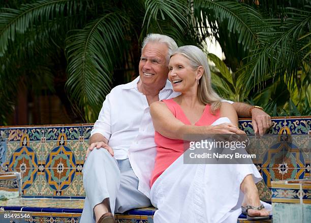 caucasian senior couple sitting on bench smiling - boca raton stockfoto's en -beelden