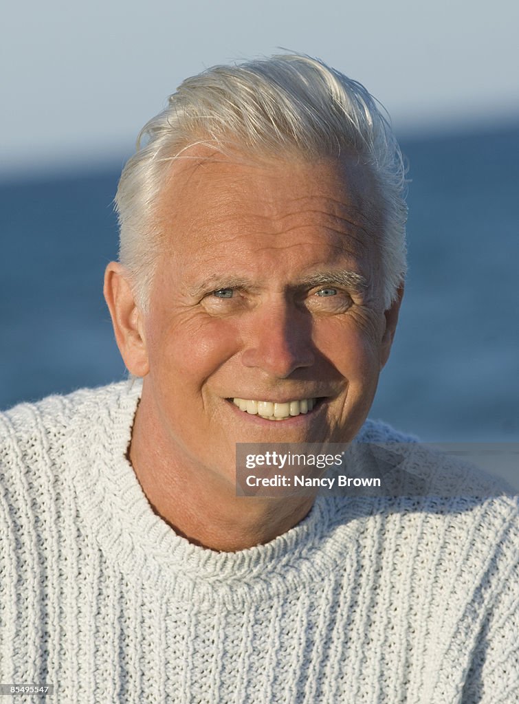 Senior Caucasian man headshot smiling on the beach