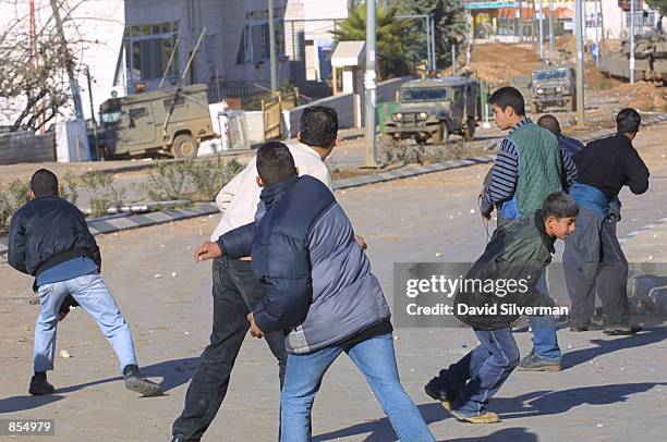 Palestinians hurl stones at Israeli army jeeps during clashes January 4, 2002 in the West Bank town of Ramallah, where the Israeli army retains an...