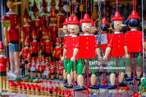 Small colorful woodcarved statues of Pinocchio are for sale as souvenirs.