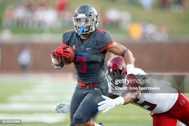 Mustangs running back Xavier Jones tries to break the tackle of Arkansas State Red Wolves linebacker Kyle Wilson during the college football game...