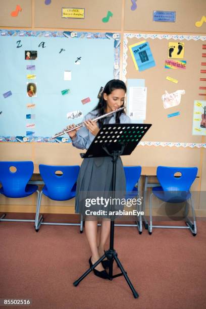 girl looking at a musical note and playing flute. - flauto foto e immagini stock