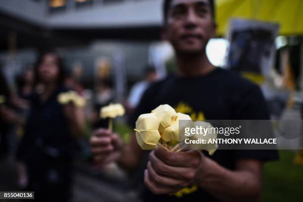 Protestor gives away miniature paper yellow umbrellas during a gathering outside the government headquarters to mark the third anniversary of mass...