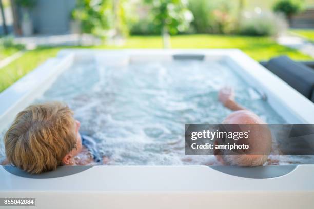 têtes de couple de personnes âgées se détendre dans le jacuzzi - bain à remous photos et images de collection