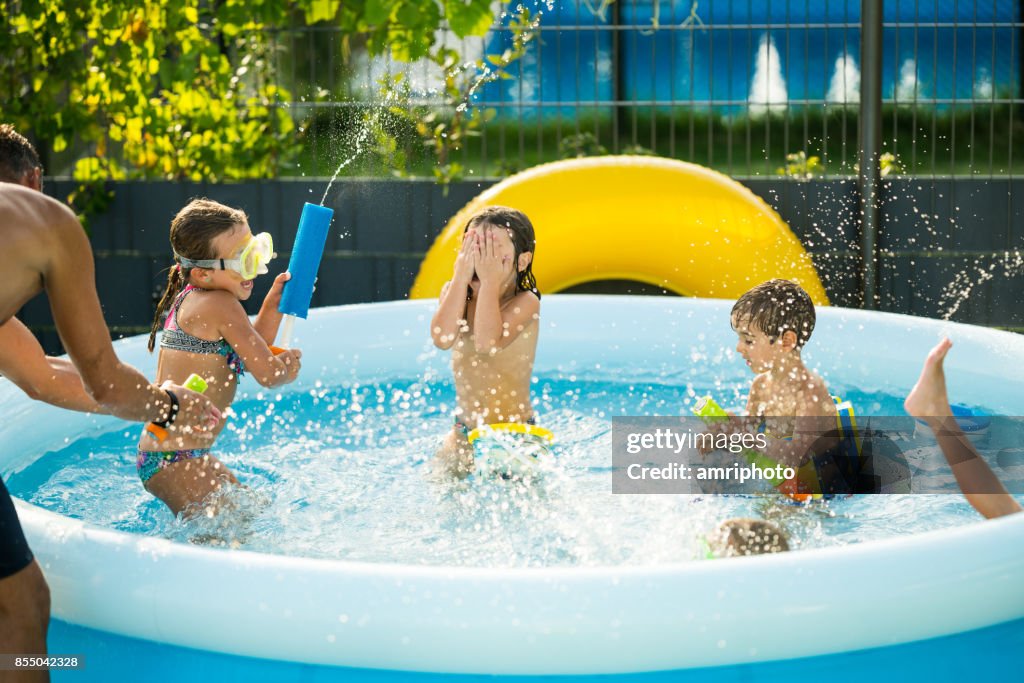 Children having fun in pool at home in garden