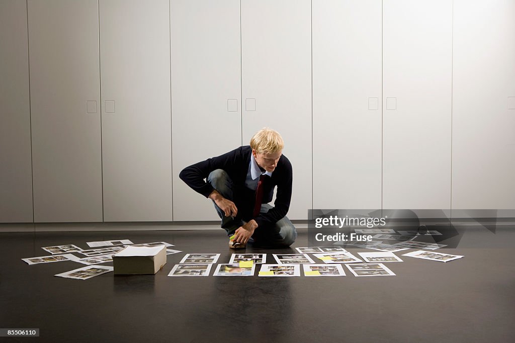 Businessman Looking at Photo Mock-ups on Floor