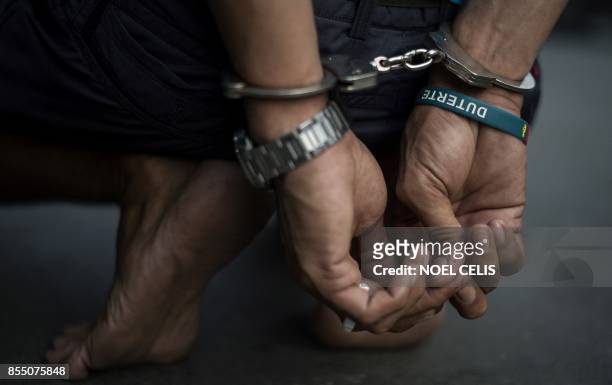 An alleged drug dealer is captured by policemen after a drug buy-bust operation on a slum area in Manila on September 28, 2017. Nearly half of...