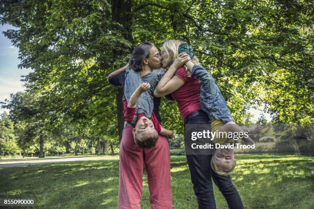 lesbian couple having fun with their children - quirky kissing foto e immagini stock