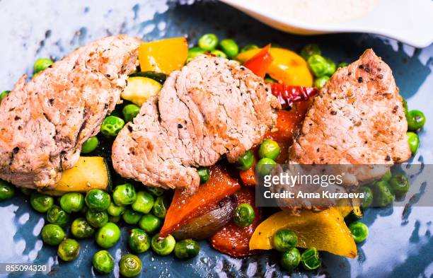 roasted pork meat fillet chops with zucchini, onion, yellow and orange bell pepper, frozen peas on a plate with cream sauce, top view - main course stock pictures, royalty-free photos & images