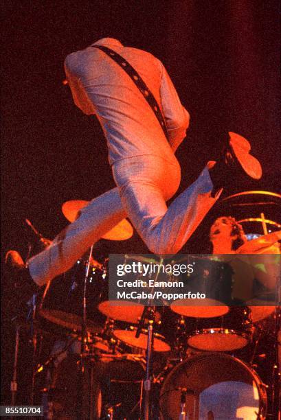 English guitarist Pete Townshend leaps in the air in front of drummer Keith Moon during a concert by The Who circa 1973.