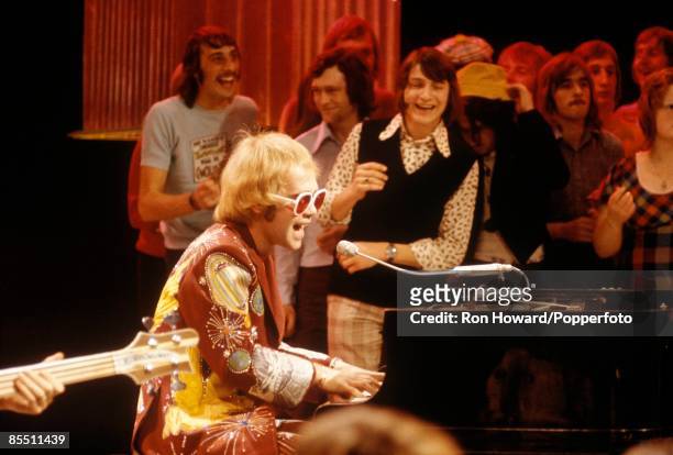 English singer and pianist Elton John performs at a grand piano in front of a studio audience on the set of a pop music television show in London in...