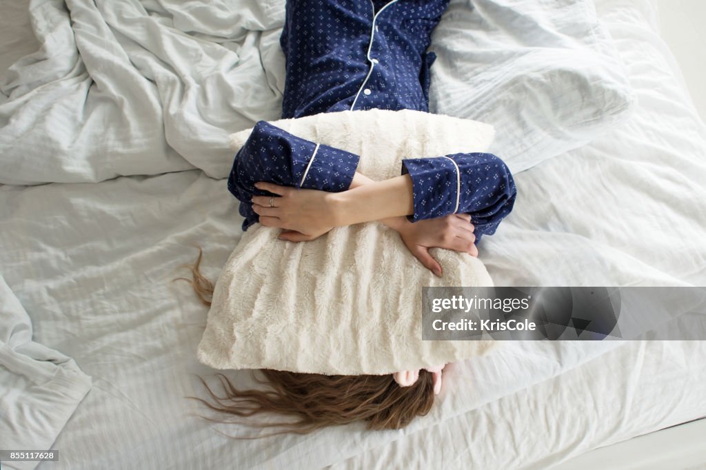 Demasiado perezoso para levantarse de la cama, una mujer cubre su rostro con una almohada