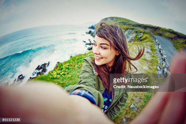 fish-eye lens of woman taking selfie on mountain by sea - ireland stock pictures, royalty-free photos & images