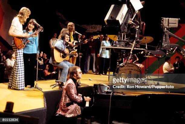 English singer and pianist Elton John performs with his band on the set of a pop music television show in London in April 1972. Members of Elton...