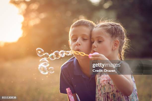 geschwister, die seifenblasen aus blase zauberstab - child blowing bubbles stock-fotos und bilder