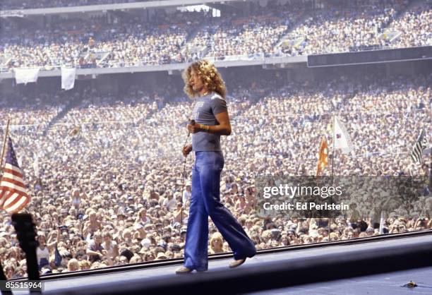 Photo of Robert PLANT and LED ZEPPELIN, Robert Plant performing on stage, wearing 'Nurses do it Better' t shirt, audience in photo