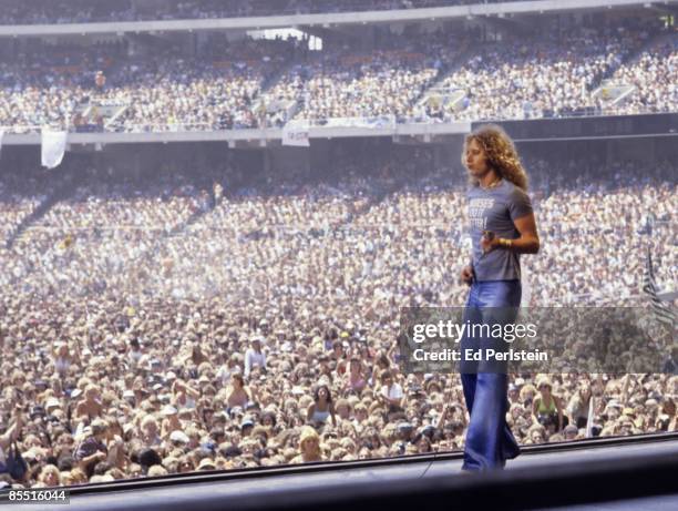 Photo of Robert PLANT and LED ZEPPELIN, Robert Plant performing on stage, wearing 'Nurses do it Better' t shirt, audience in photo