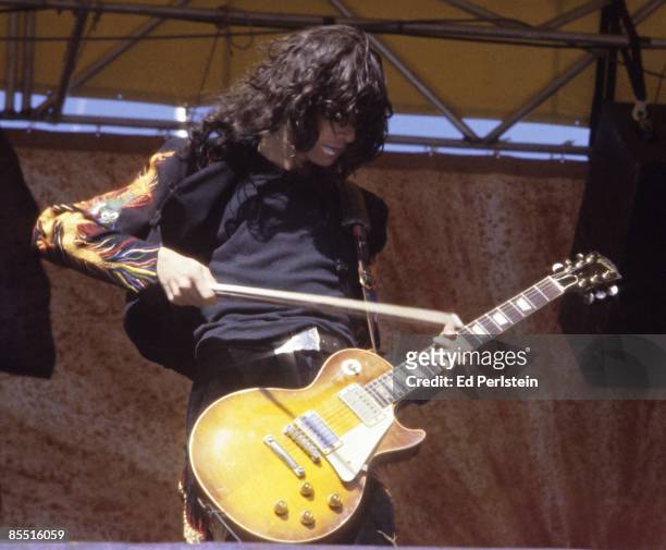 Photo of Jimmy PAGE and LED ZEPPELIN, Jimmy Page performing on stage, playing a Gibson Les Paul Guitar with a cello bow