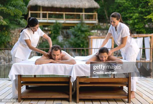 happy couple getting a back massage at the spa - massage couple stock pictures, royalty-free photos & images