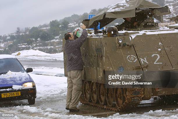 Jewish settler brings hot coffee to Israeli soldiers guarding a checkpoint January 10, 2002 on the outskirts of the West Bank town of Bethlehem. The...