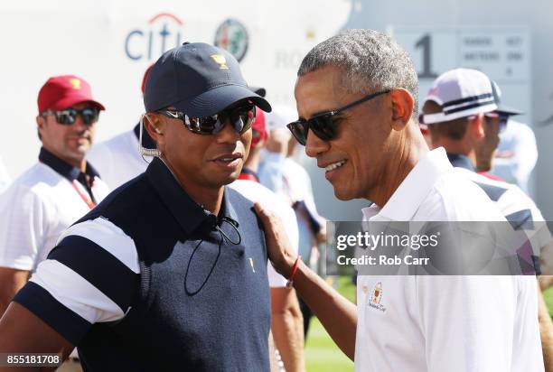 Captain's assistant Tiger Woods of the U.S. Team speaks to former U.S. President Barack Obama on the first tee during Thursday foursome matches of...