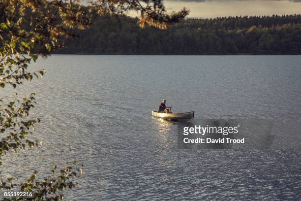 man in canoe on a lake in sweden - david trood stockfoto's en -beelden
