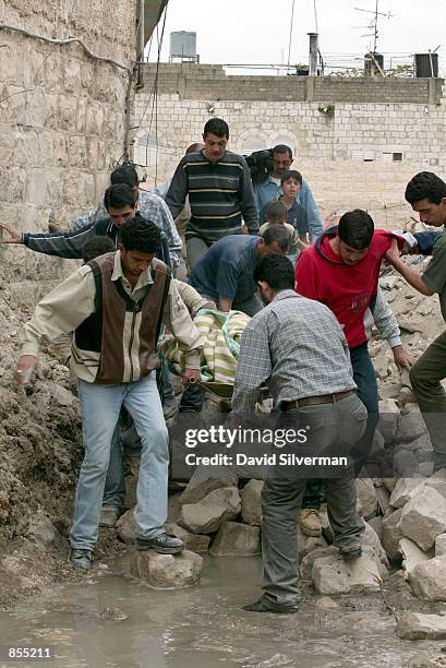 Palestinians pull the sheet-covered body of Zaha Freiteh from the rubble of her home in the old town of the West Bank city of Nablus April 15, 2002...