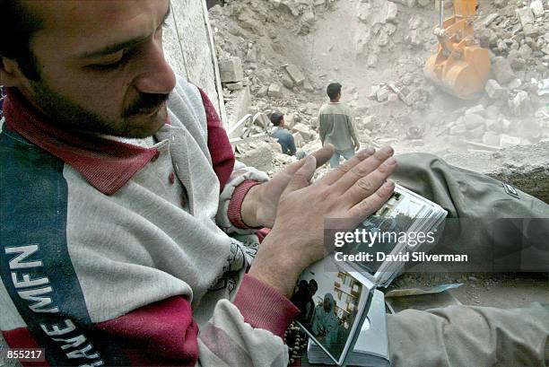 Bashar Freiteh looks at his dead aunt Zaha Freiteh's photo album which was found in the rubble of her home in the old town of the West Bank city of...