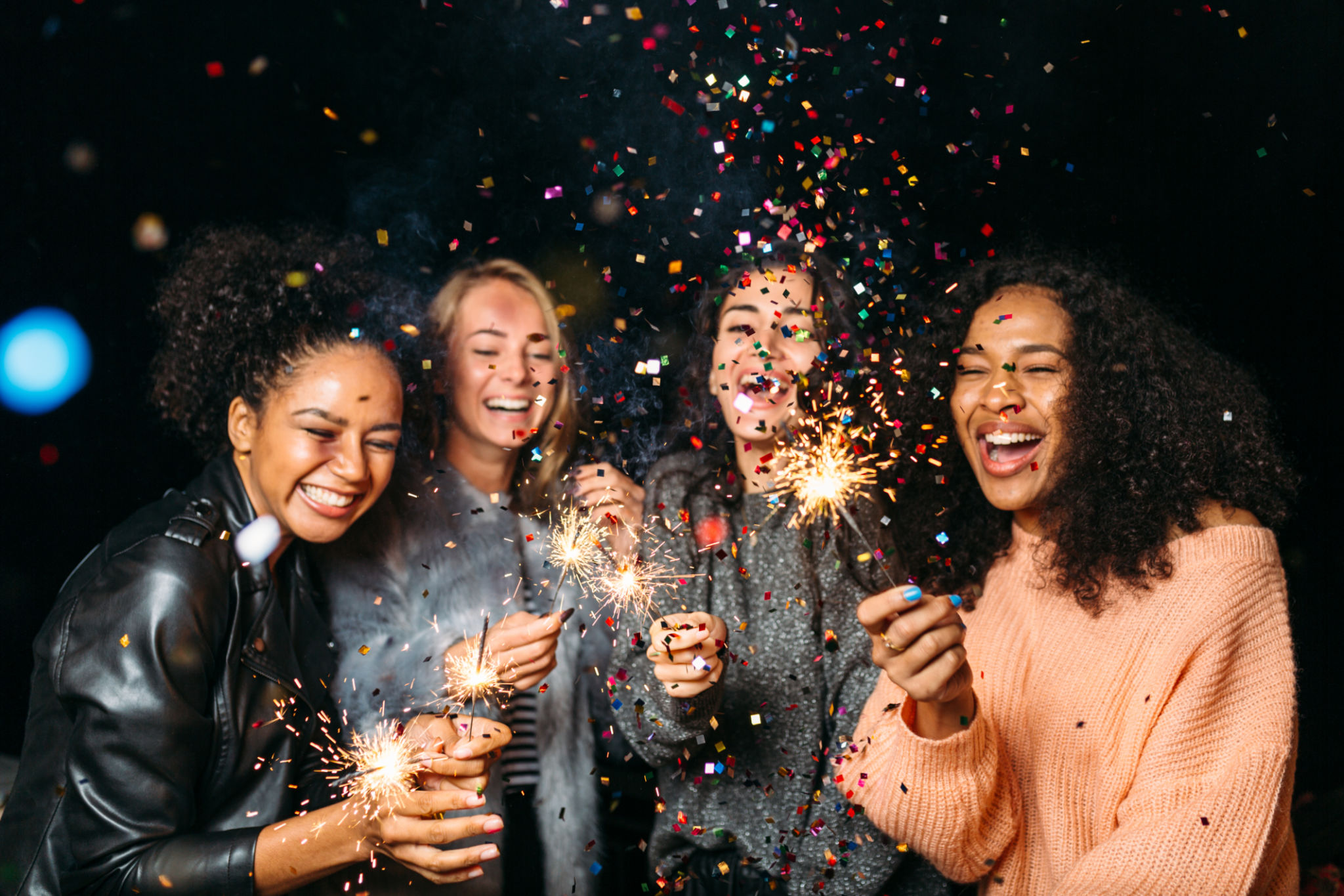 Happy friends. Group of smiling women holding sparklers under confetti Happy friends. Group of smiling women holding sparklers under confetti