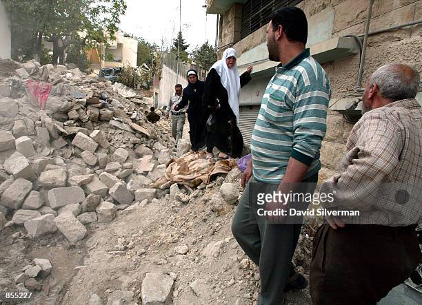 Palestinian women walk carefully through the rubble of Zaha Freite's home in the old town of the West Bank city of Nablus April 15, 2002 where...