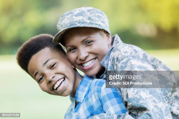 schöne militärische mutter umarmt preteen sohn während wiedervereinigung nach ihrer tour - black family reunion stock-fotos und bilder