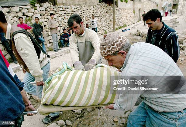 Palestinians evacuate the sheet-covered body of Zaha Freiteh after she was found in the rubble of her home in the old town of the West Bank city of...