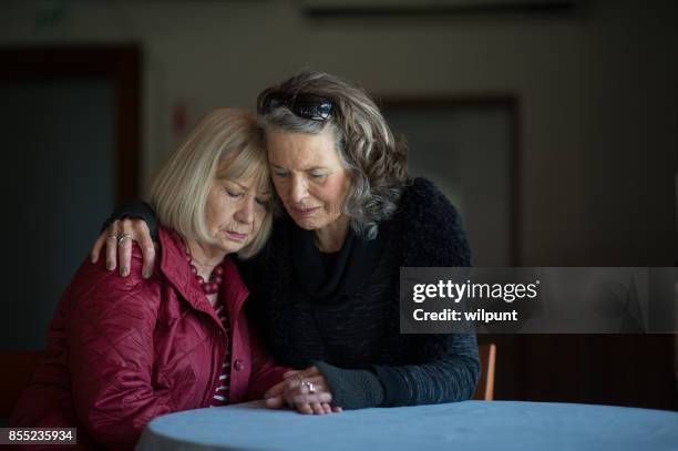 two senior ladies supporting one another - mourner imagens e fotografias de stock