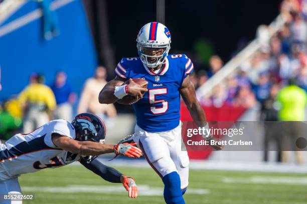 Tyrod Taylor of the Buffalo Bills runs with the ball as Justin Simmons of the Denver Broncos dives to trip Taylor up during the second half on...