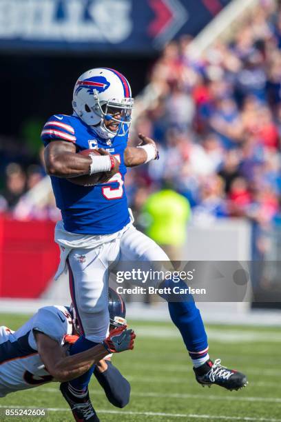 Tyrod Taylor of the Buffalo Bills runs with the ball as Justin Simmons of the Denver Broncos dives to trip Taylor up during the second half on...