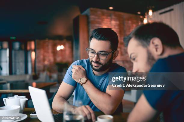 two handsome friends drinking coffee and surfing the net in cafe restaurant - blog news stock pictures, royalty-free photos & images